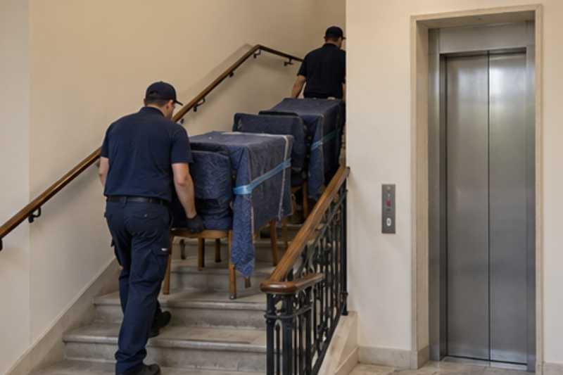Une table et des chaises sous couverture de déménagement, dans une cage d'escalier d'immeuble, déménagement de Paris vers l'Arménie
