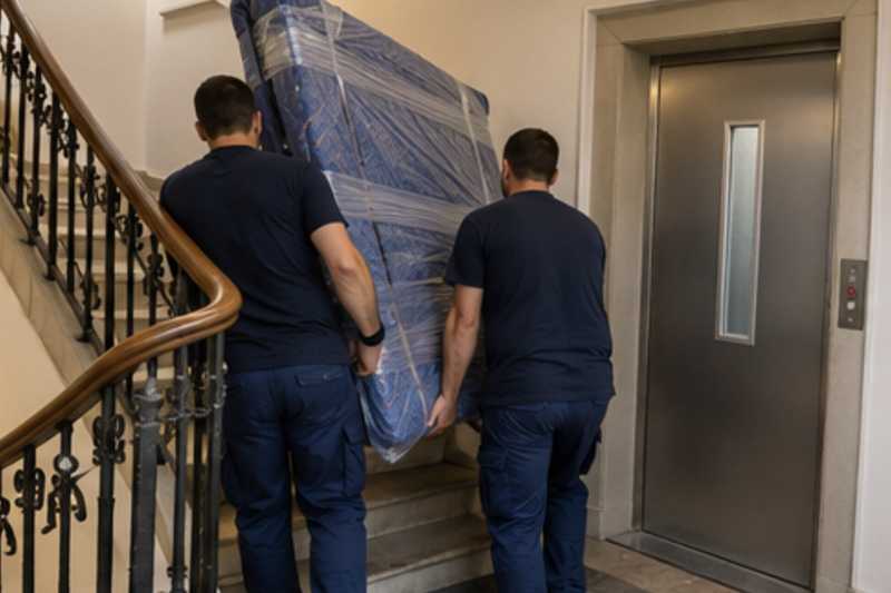 Un sommier double sous couvertures capitonnées et film étirable, dans une cage d'escalier d'immeuble, déménagement de Paris vers la Birmanie