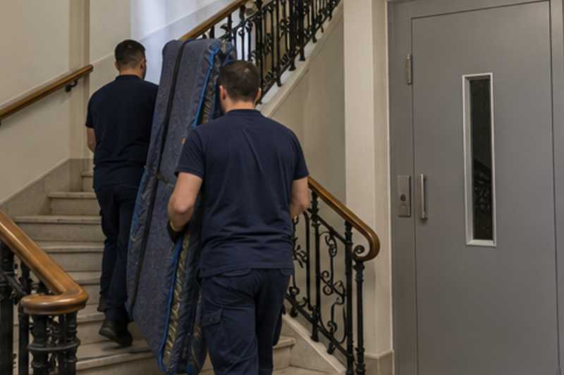Les montants d'une bibliothèque démontée sous housse zippée, dans une cage d'escalier d'immeuble, déménagement de Paris vers le Kosovo