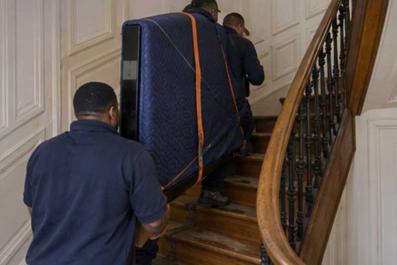 Un grand téléviseur écran plat sous couverture de déménagement, dans un escalier tournant en bois d'immeuble ancien, déménagement de Paris vers le Libéria